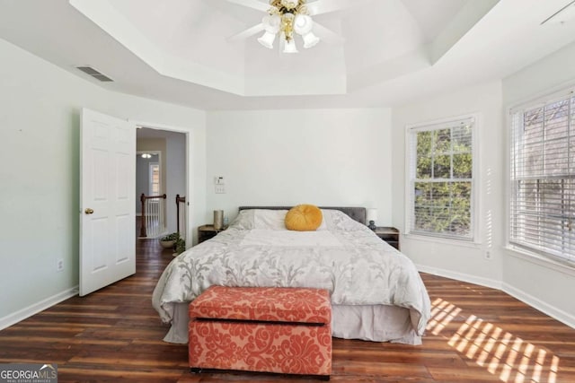 bedroom featuring a raised ceiling, ceiling fan, and dark wood-type flooring