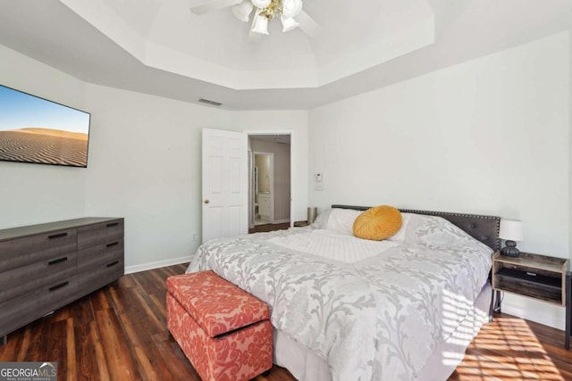 bedroom with a raised ceiling, ceiling fan, and dark wood-type flooring