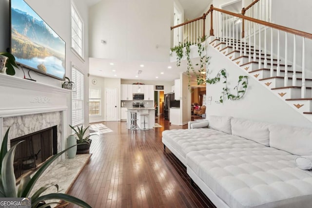 living room featuring dark hardwood / wood-style flooring, a towering ceiling, and a premium fireplace