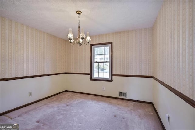 spare room with carpet and a notable chandelier