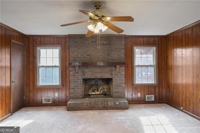 unfurnished living room featuring a fireplace, ceiling fan, ornamental molding, and wood walls