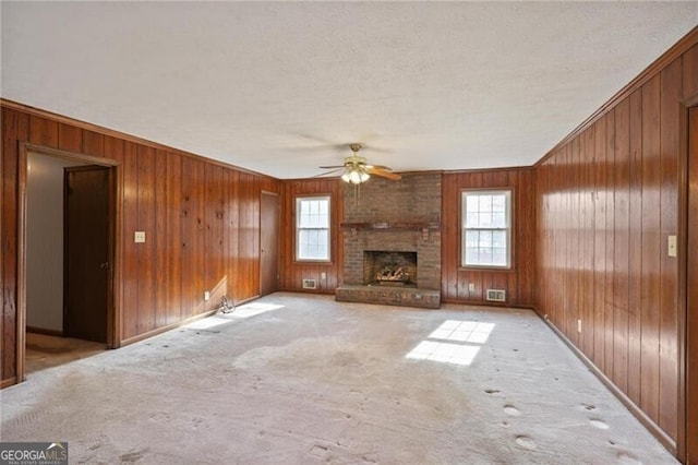 unfurnished living room featuring ceiling fan, light colored carpet, and a fireplace