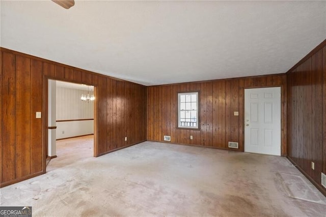 carpeted spare room with an inviting chandelier