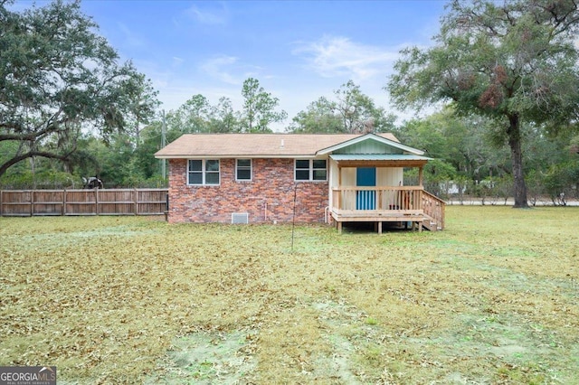 rear view of house featuring a deck, brick siding, fence, a yard, and crawl space