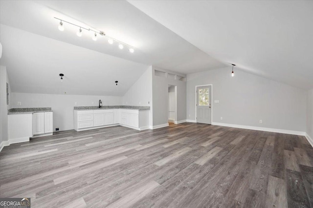 bonus room with light wood-type flooring, wet bar, baseboards, and vaulted ceiling