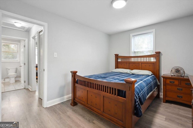 bedroom with attic access, baseboards, and wood finished floors