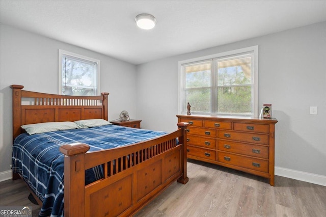 bedroom featuring multiple windows, light wood-style flooring, and baseboards