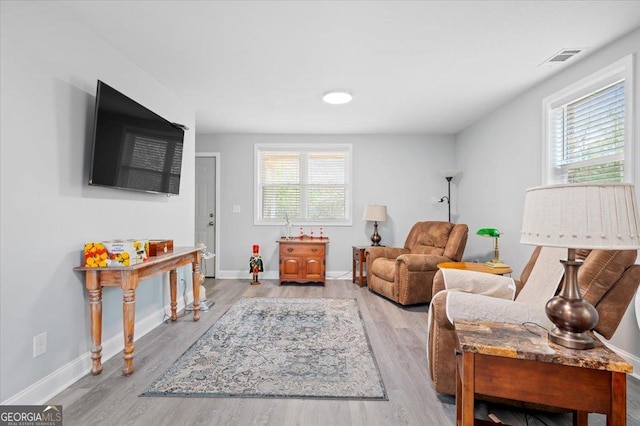 living area featuring light wood-style floors, visible vents, and baseboards