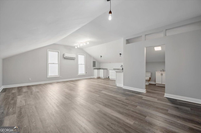 unfurnished living room featuring dark wood-style floors, baseboards, vaulted ceiling, and an AC wall unit