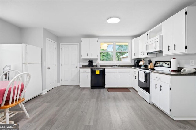 kitchen with white appliances, light wood finished floors, white cabinets, dark countertops, and a sink