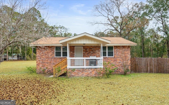 single story home featuring covered porch, a front yard, fence, and brick siding