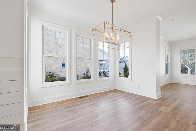 unfurnished dining area featuring baseboards, a chandelier, visible vents, and light wood-style floors