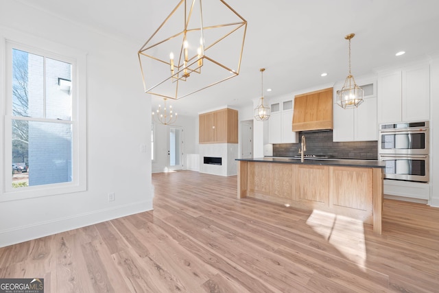kitchen featuring pendant lighting, stainless steel double oven, dark countertops, and white cabinets