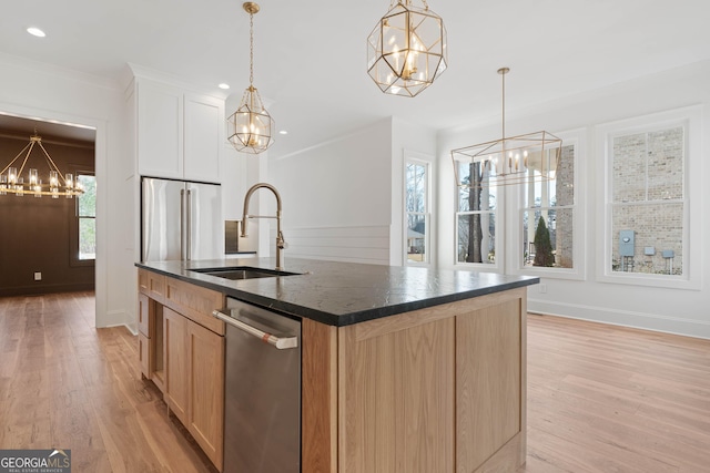 kitchen featuring a kitchen island with sink, stainless steel appliances, a sink, decorative light fixtures, and an inviting chandelier