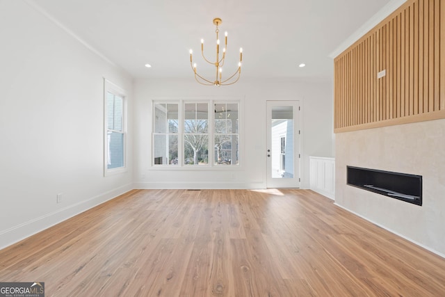 unfurnished living room featuring light wood finished floors, baseboards, a notable chandelier, and recessed lighting