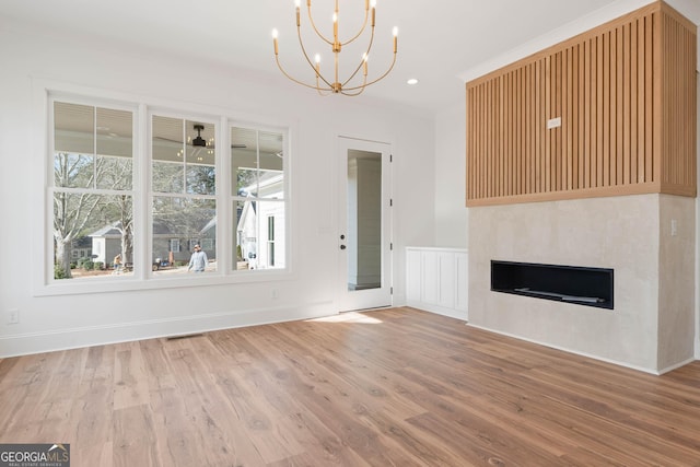 unfurnished living room with a fireplace, recessed lighting, visible vents, wood finished floors, and ceiling fan with notable chandelier