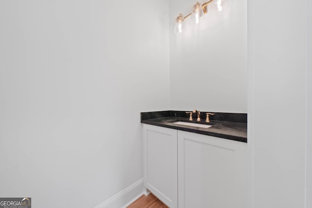 bathroom featuring baseboards, wood finished floors, and vanity