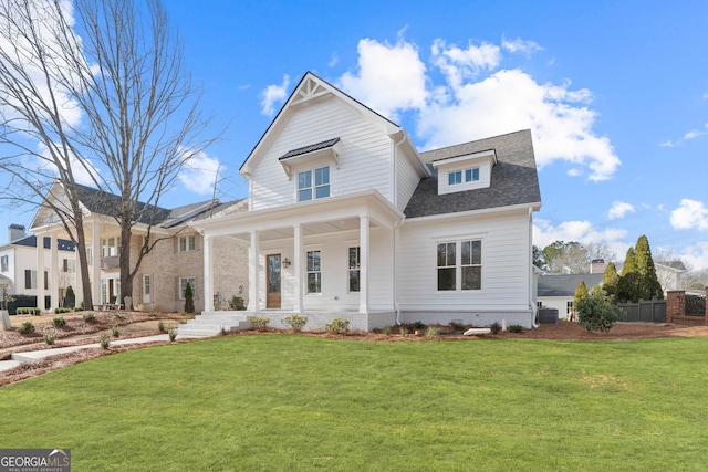 view of front facade featuring covered porch, a shingled roof, a front lawn, and cooling unit