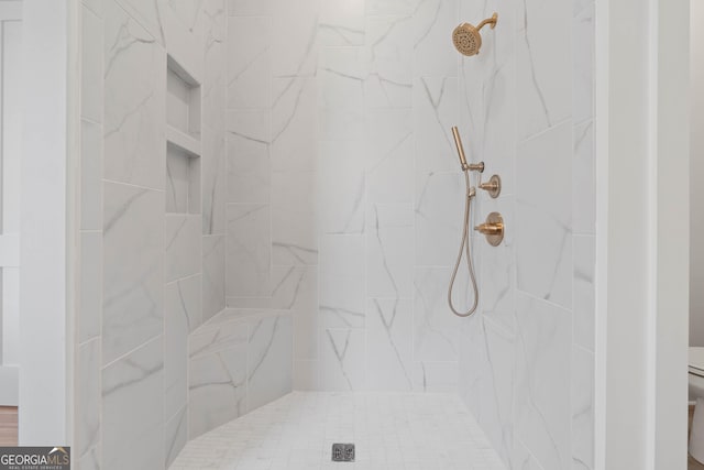bathroom with a tile shower and toilet