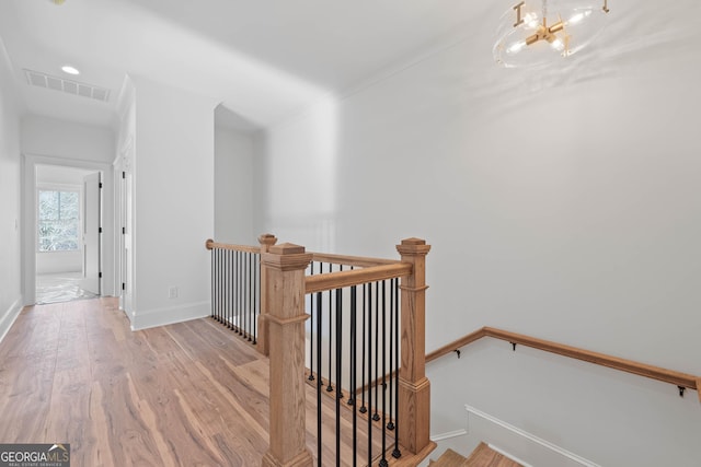 corridor with a notable chandelier, an upstairs landing, baseboards, visible vents, and light wood finished floors