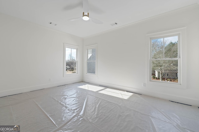unfurnished room with a wealth of natural light, visible vents, and ceiling fan