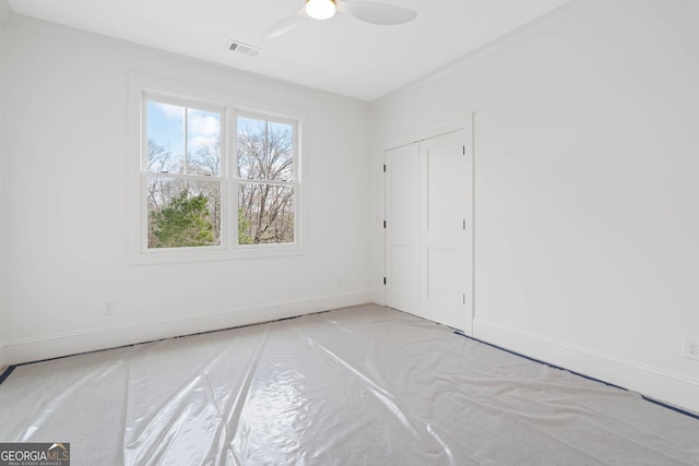unfurnished room with a ceiling fan, visible vents, and baseboards