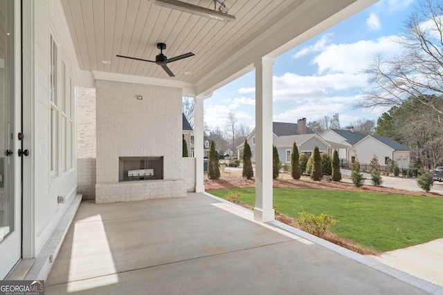 view of patio with an outdoor brick fireplace, a residential view, and a ceiling fan