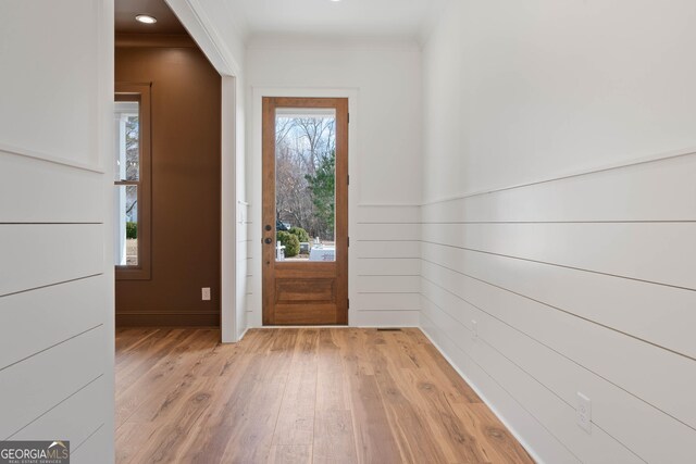 foyer entrance with ornamental molding and light wood-type flooring