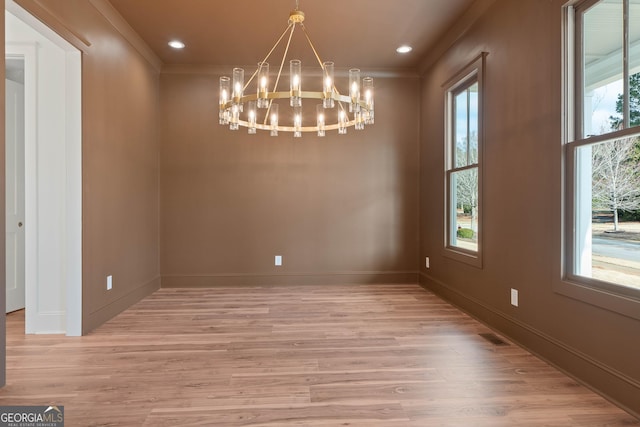 unfurnished dining area with light wood finished floors, baseboards, an inviting chandelier, crown molding, and recessed lighting