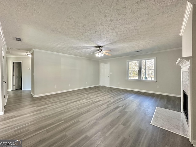 unfurnished living room with a textured ceiling, dark wood-type flooring, ornamental molding, and ceiling fan