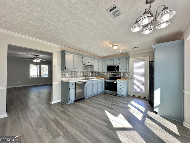 kitchen with pendant lighting, stainless steel appliances, sink, and hardwood / wood-style floors