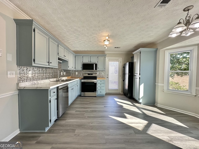 kitchen featuring pendant lighting, sink, dark wood-type flooring, appliances with stainless steel finishes, and backsplash