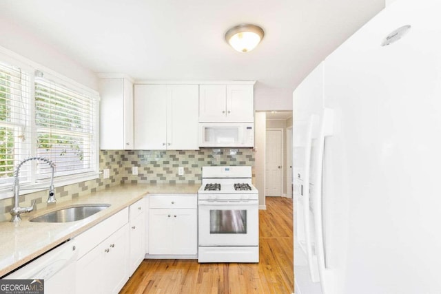 kitchen featuring sink, light hardwood / wood-style flooring, white appliances, decorative backsplash, and white cabinets