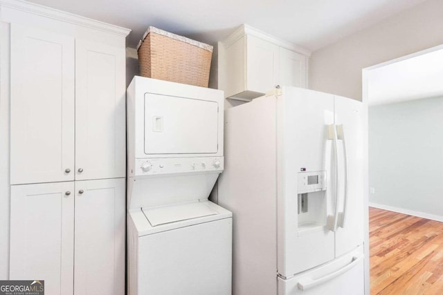 laundry room with hardwood / wood-style floors and stacked washer / dryer