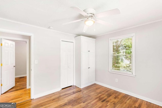 unfurnished bedroom with ceiling fan, light wood-type flooring, ornamental molding, and a closet