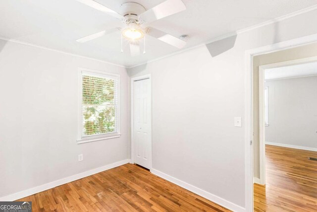 empty room featuring wood-type flooring, ceiling fan, and crown molding