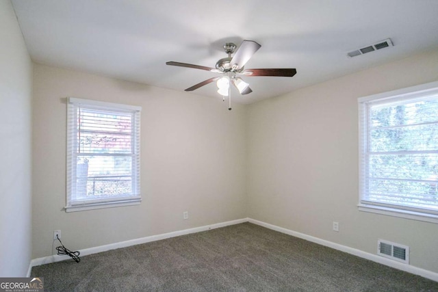 empty room with ceiling fan and dark carpet