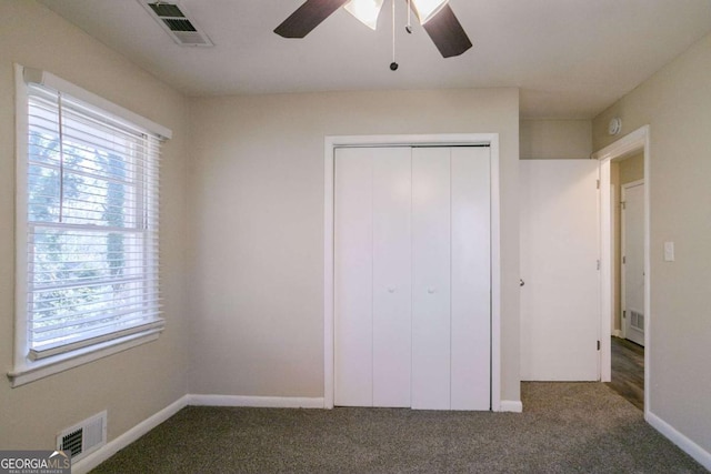 unfurnished bedroom featuring ceiling fan, a closet, and dark colored carpet