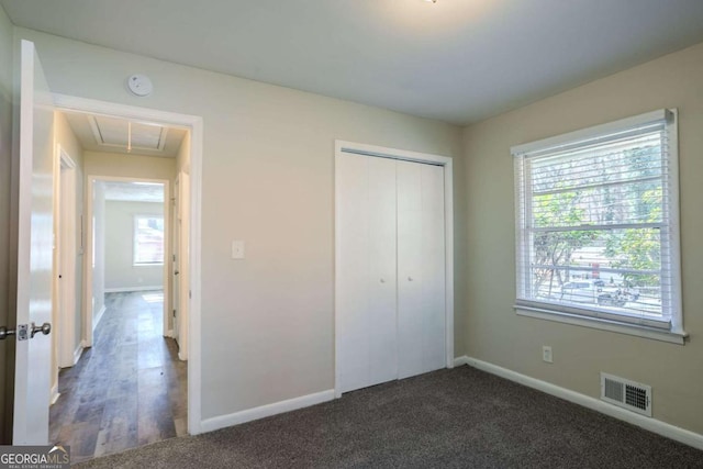 unfurnished bedroom with dark carpet and a closet