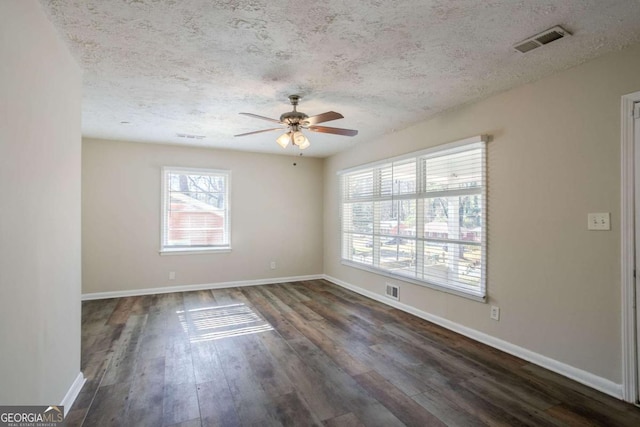 unfurnished room with a textured ceiling, a healthy amount of sunlight, and dark hardwood / wood-style floors