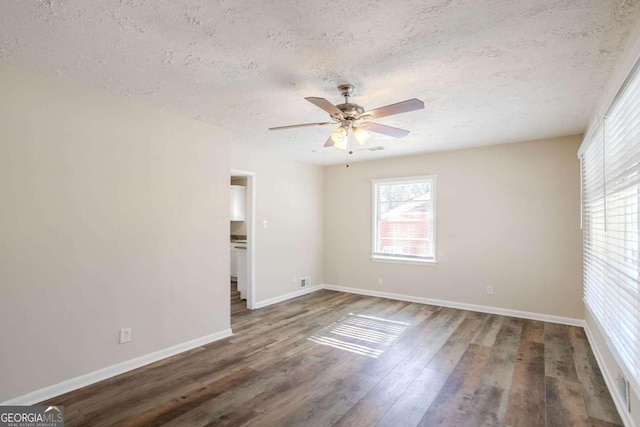 spare room with ceiling fan, dark wood-type flooring, and a textured ceiling