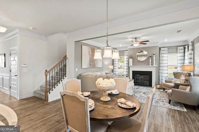 dining space featuring ceiling fan, ornamental molding, and dark wood-type flooring