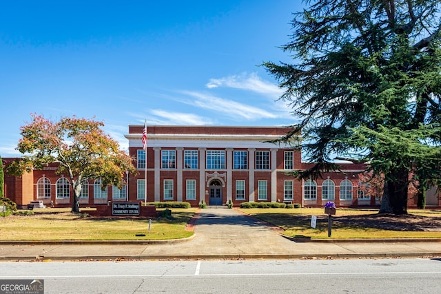 neoclassical home featuring a front lawn