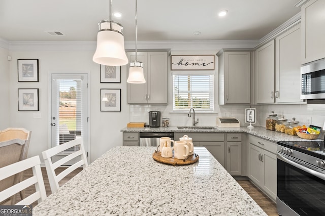 kitchen featuring a wealth of natural light, sink, hanging light fixtures, and stainless steel appliances