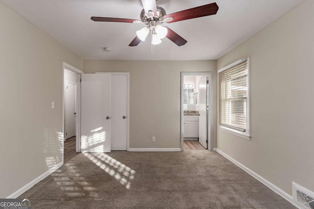 unfurnished bedroom featuring ceiling fan, light colored carpet, and ensuite bath