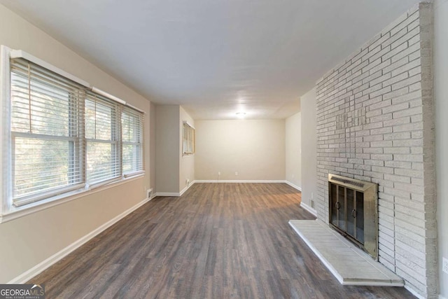 unfurnished living room featuring dark hardwood / wood-style flooring and a brick fireplace