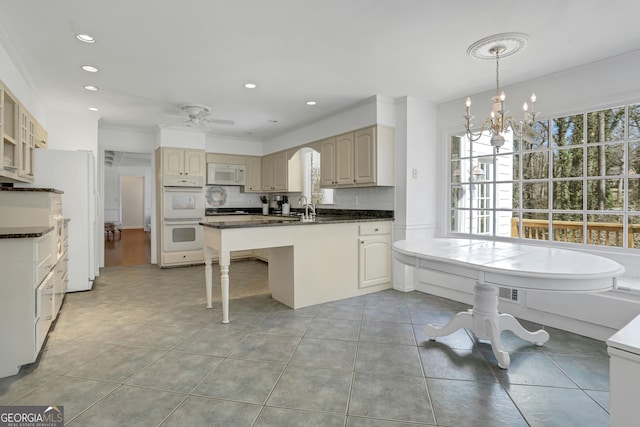 kitchen featuring tasteful backsplash, white appliances, decorative light fixtures, light tile patterned floors, and sink