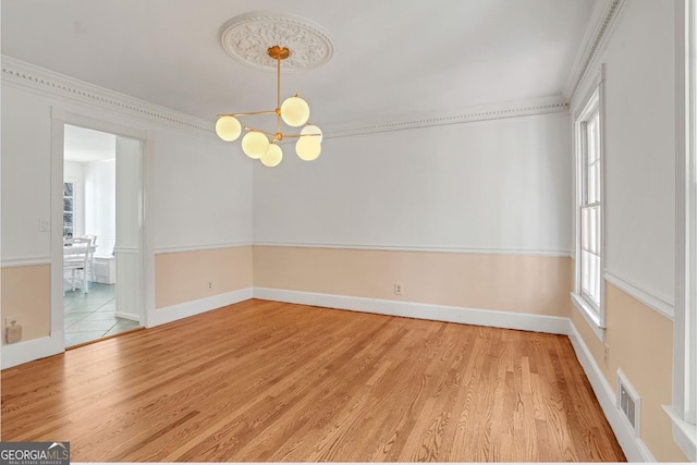 unfurnished room featuring hardwood / wood-style floors, an inviting chandelier, and ornamental molding