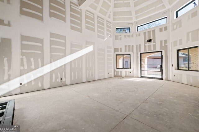 unfurnished living room featuring concrete floors and a high ceiling