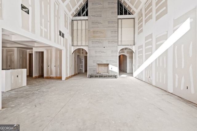 unfurnished living room with a towering ceiling and concrete floors